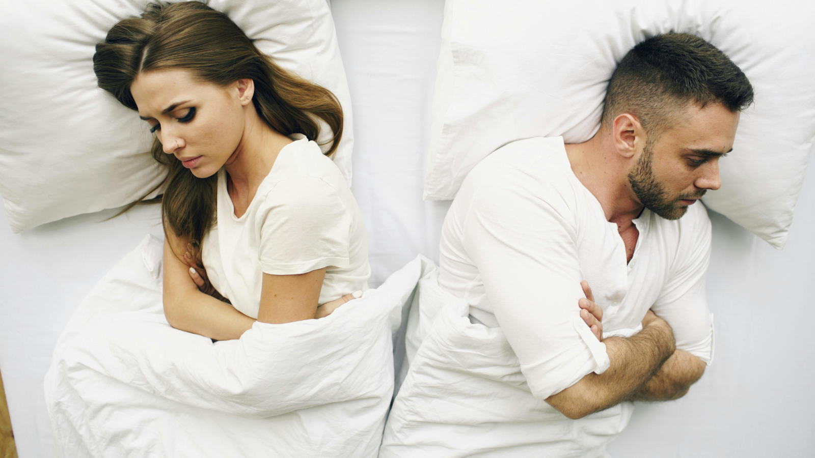 Ein Paar liegt abgewandt von einander im Bett, Symbolbild für Bindungsangst in der Sexualität und sexuelle Blockade wegen der Bindungsangst