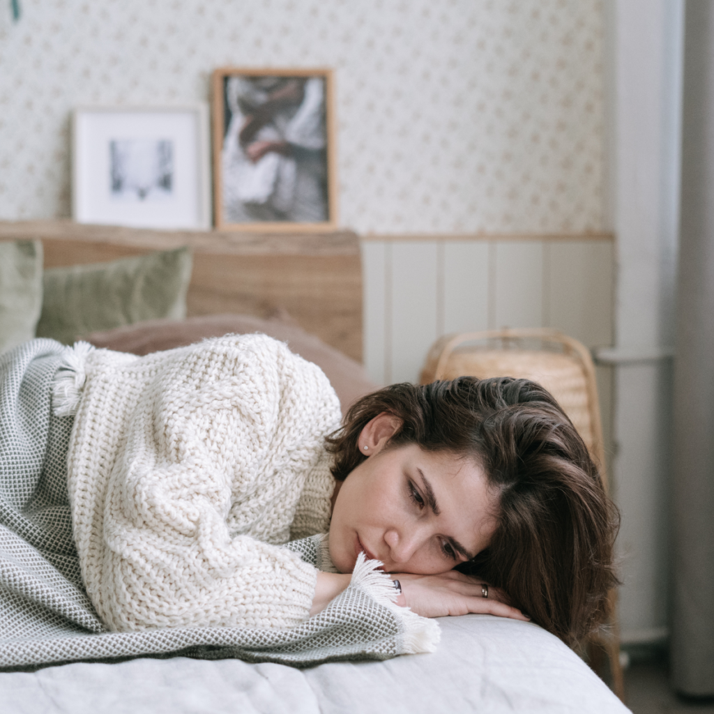 Eine Frau liegt angezogen in ihrem Bett, ein Symbolbild f&uuml;r Shutdown